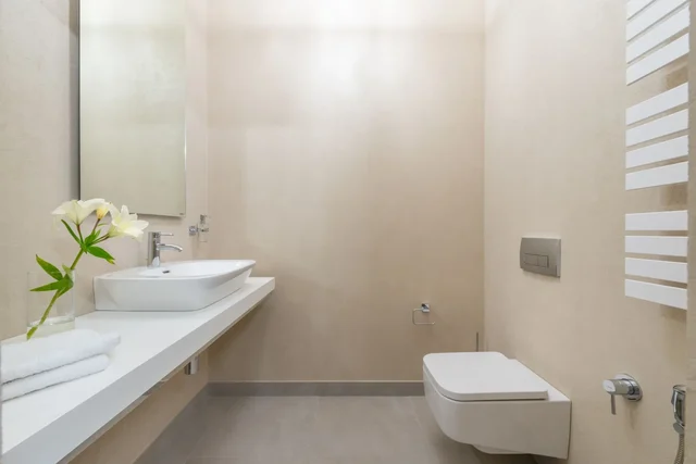 Svijetla kupaonica s modernom WC školjkom i diskretnom WC daskom u toplim neutralnim tonovima.